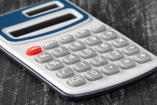 Close-up view of electronic calculator on wooden background.