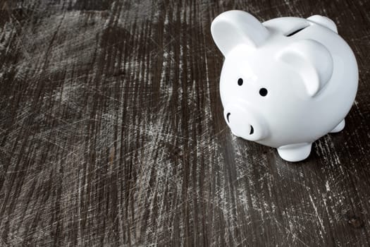 Piggy bank on the scratched black wooden background