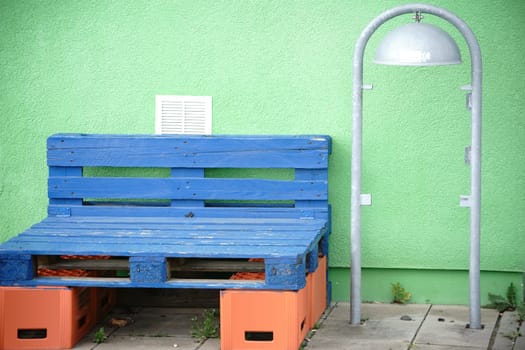 A colorful homemade simple bench made of blue pallets and empty beer crates.