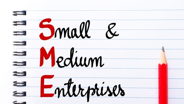 SME Small and Medium Enterprises written on notebook page with red pencil on the right