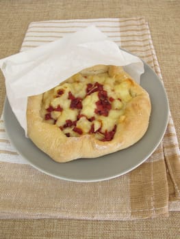 Pizza bread street food with cheese and ham in a sandwich paper bag