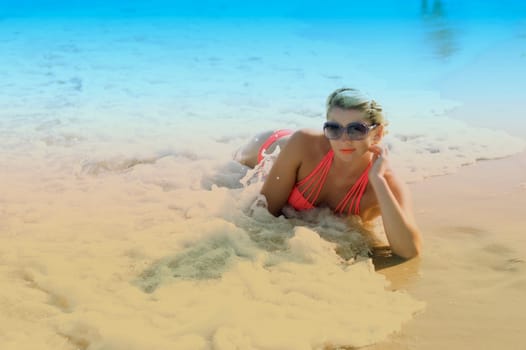 the beautiful girl lies in sea waves, a blue background