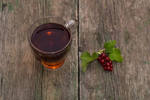 transparent cup of tea and branch of red currant on a shabby table, top view, a subject summer berries