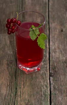 the tall glass of juice decorated with a red branch of currant, a subject drinks and berries