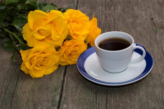 bouquet of beautiful roses and cup of coffee on a shabby table, a festive card on a subject flowers