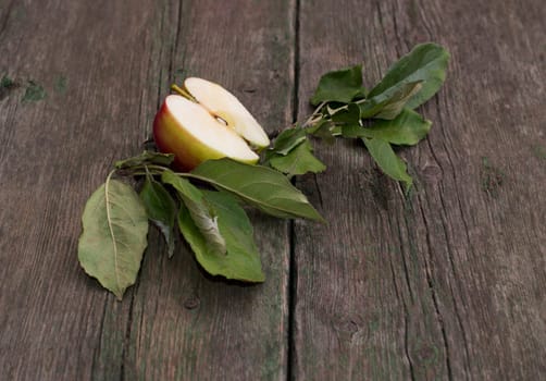 the cut apple with leaves on an old wooden table, a subject fruit