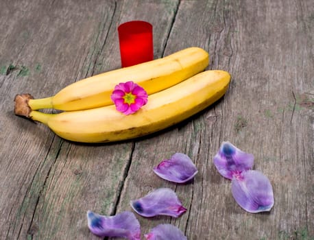 two bananas the decorated with lilac petals and red candle, a subject fruit
