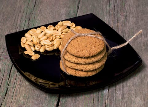 black plate with a peanut and oatmeal cookies, a sweet subject