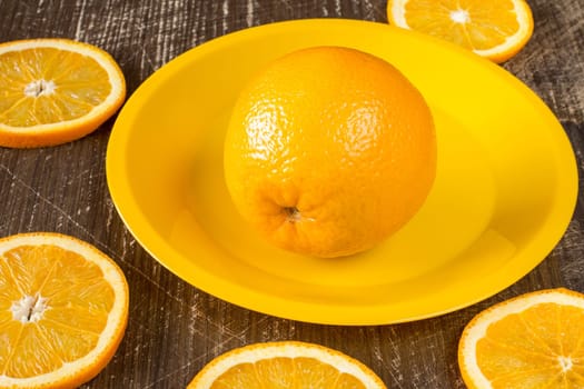 Orange slices and  whole orange fruit on a yellow plate