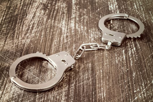 Close-up view of handcuffs on the wooden background.Filtered image.