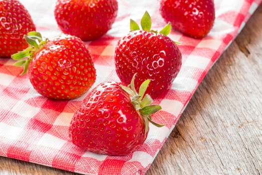 Fresh strawberries on red and white checkered napkin.