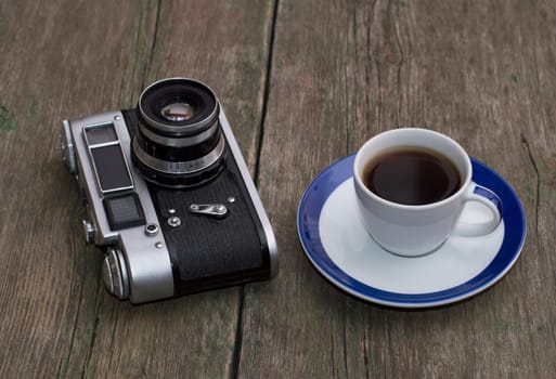 the old camera and cup of coffee on a wooden table, a retro subject