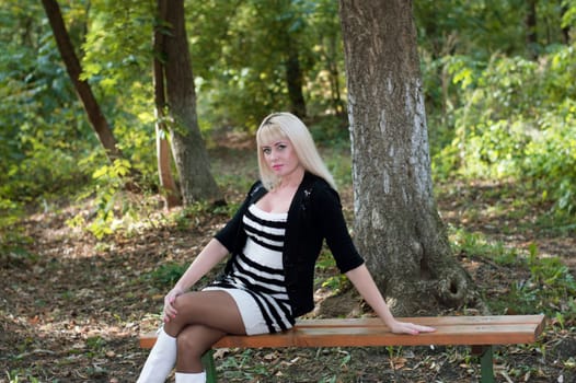 the beautiful woman sits on a bench in autumn park, an image subject the woman and the beautiful nature, seasons