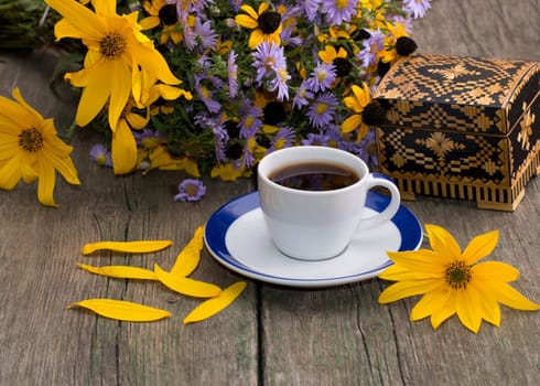 cup of coffee, casket, flower, petals and wild flowers on an old table, a still life, a festive card, a greeting card, a subject drinks and flowers