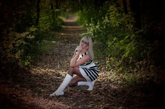 the beautiful woman sat down on a forest footpath, a season fall, the image in a dark key