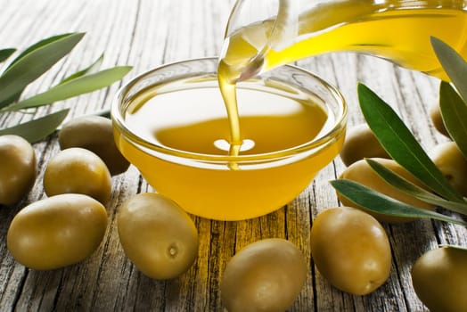 Bottle pouring virgin olive oil in a bowl close up