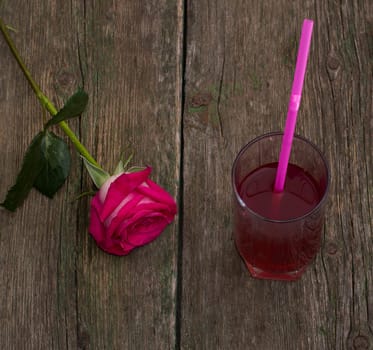 one red rose and glass of juice, on an old table, a subject flowers and drinks