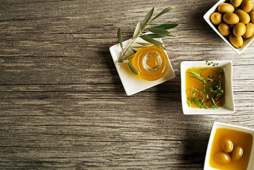 Olive oil with fresh herbs on wooden background