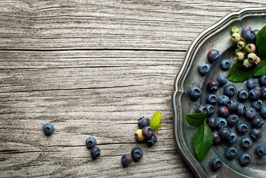 Juicy and fresh blueberries with green leaves on rustic table