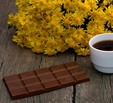 bouquet of yellow flowers, tile a chocolate and coffee, on a wooden table, a still life, a subject flowers and drinks