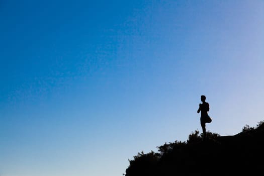 man on top of the mountain practing yoga at the sunset