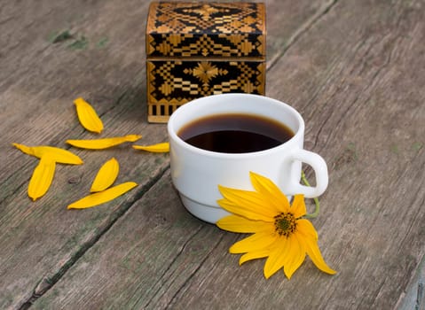 casket, petals, yellow flower and coffee, on a wooden table, a still life, a subject flowers and drinks