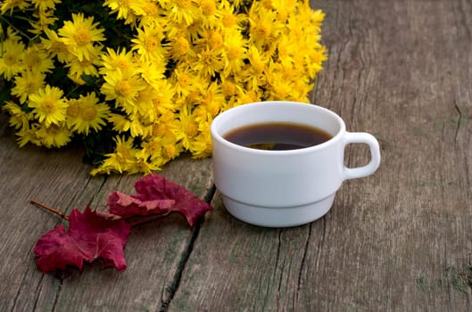 bouquet of yellow flowers, red leaf and coffee, still life on a subject drinks flowers and fall
