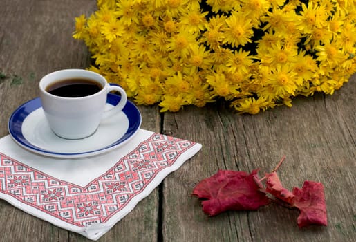 still life, coffee on a napkin, a bouquet of yellow flowers and a red leaf, on a wooden table, fall, a subject drinks