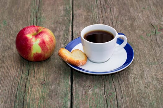 coffee on a saucer, cookies and one apple, on a wooden table, a subject food and drinks