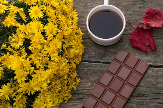 chocolate, red leaf, bouquet of yellow flowers and coffee, on a wooden table, a still life, a subject fall