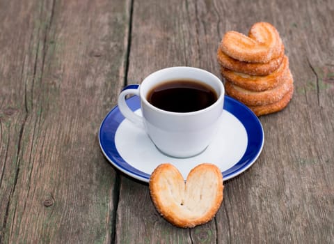 coffee on a saucer, and a column from cookies, on a wooden table, a subject food and drinks