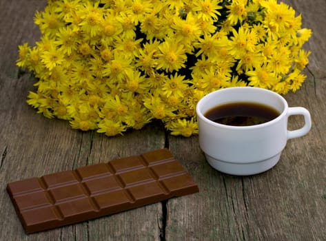 bouquet of beautiful flowers, chocolate and coffee, on a wooden table, a subject food and drinks