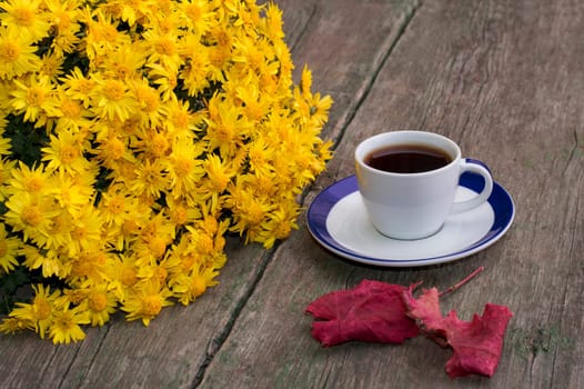coffee, a bouquet of yellow flowers and nearby a red leaf, on a wooden table, fall, a still life a subject drinks