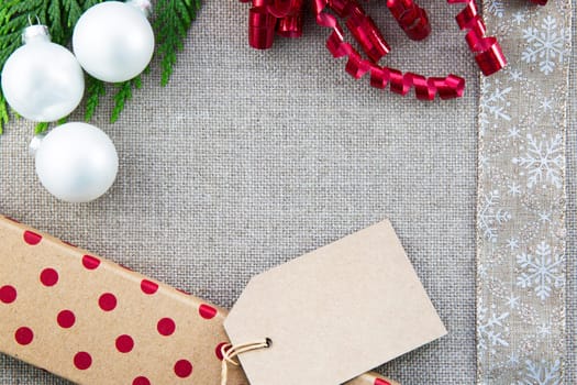 Gift box, ribbons and Christmas ornaments  on linen creating frame with copy space in center.