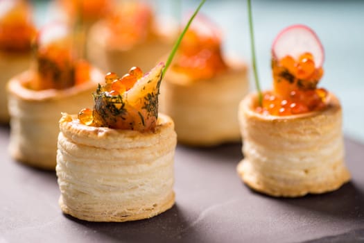 Delicious appetizers with graved salmon and golden caviar served in puff pastry towers
