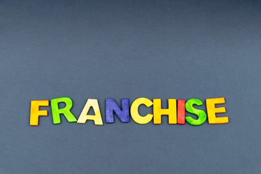 Word FRANCHISE created of wood letters on dark background, business concept, copy space available