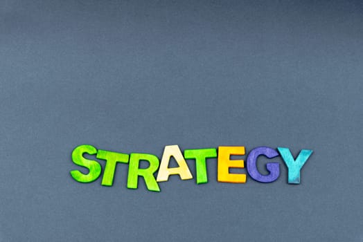 Word STRATEGY created of wood letters on dark background, business concept, copy space available
