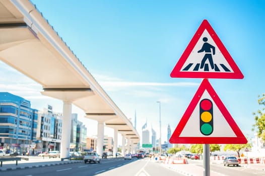 Pedestrian traffic sign and traffic light. The background blurry car and city streets.