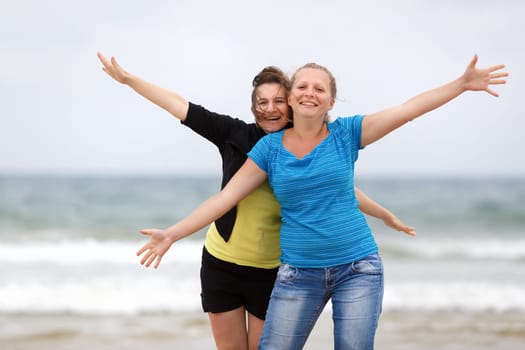 Two happy women on the beach with open arms enjoying their freedom. Shallow depth of field.