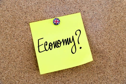 Yellow paper note pinned on cork board with Great Britain flag thumbtack, written text ECONOMY, United Kingdom exit from European Union concept