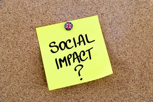 Yellow paper note pinned on cork board with Great Britain flag thumbtack, written text SOCIAL IMPACT ?, United Kingdom exit from European Union concept