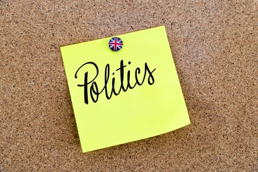 Yellow paper note pinned on cork board with Great Britain flag thumbtack, written text POLITICS, United Kingdom exit from European Union concept