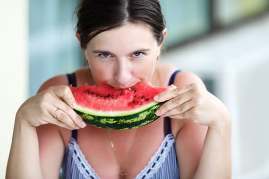 Pretty young woman eating fresh juicy watermelon. Shallow depth of field. Selective focus on the model's face.