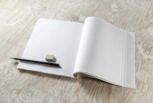 Blank opened brochure with a pencil and eraser with soft shadows on light wooden background. Blank Template for your design. Responsive design template.