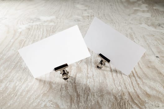 Blank business cards with soft shadow on light wooden table background. Two blank business cards. Mock-up for branding identity. Selective focus.