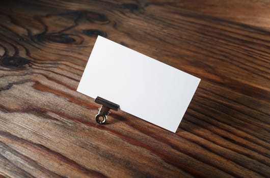 Photo of blank business card on vintage wooden background. Blank white business card. Mockup for branding identity. Blank ID template.