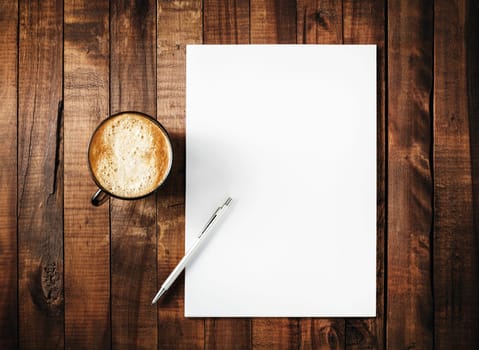 Blank branding template on vintage wooden table background. Letterhead, coffee cup and pen. Blank stationery. Mock-up for branding identity for design portfolios. Top view.