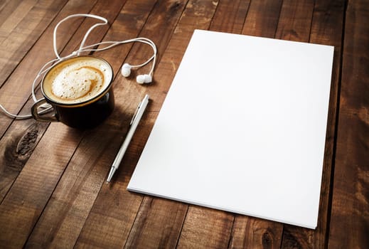 Blank branding template on vintage wooden table background. Blank letterhead, coffee cup, headphones and pen. Photo of blank stationery. Mock-up for your design. Responsive design template.