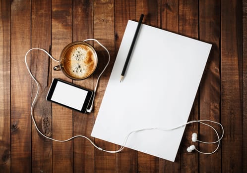 Corporate identity template on vintage wooden table background. Responsive design mock-up. Paper, letterhead, coffee cup, smartphone, pencil and headphones. Top view.