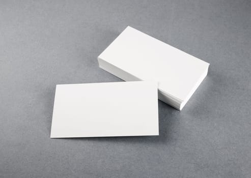 Photo of blank business cards with soft shadows on gray background. Mock-up for branding identity. Studio shot.